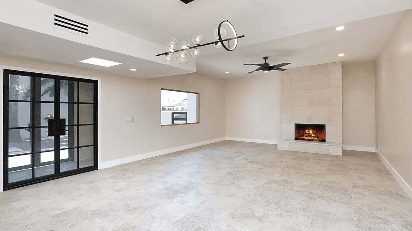 A renovated living room with fireplace and oversized casements.